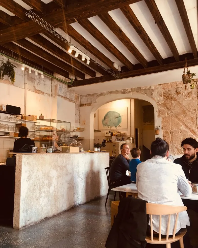 Stone-walled coffee bar and customers inside Cafè Riutort in Palma